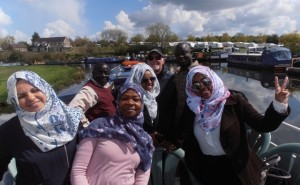 Smiles in the sun as the boat passes moored boats and caravans