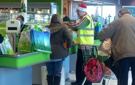 One of Santa's little helpers helps an Asda shopper pack her bags