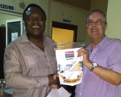 Rotary Club of Brusubi President Sapard Kalala presents a banner to Rtn Jim