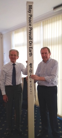 Rotarian John Niblett, of the Rotary Club of Oadby Launde, presents the Rotary Peace Pole to Frazer Robson, of the Rotary Club of Leicester Novus