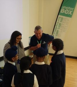 Rtn Alan Jones shows teacher Miss Krishna Popat and some of her Year 3 class some of the items included in the Shelterbox box