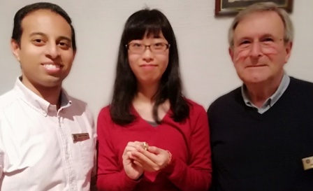 Mai Tsumura holds her pin presented to her by Rotarian John Saunders and Novus president Jason Chauhan