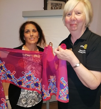 Incoming president Maya Vansia receives a scarf from secretary Pam Spokes. The scarf bears the logo of the theme for 2019-2020 "Rotary Connects The World"